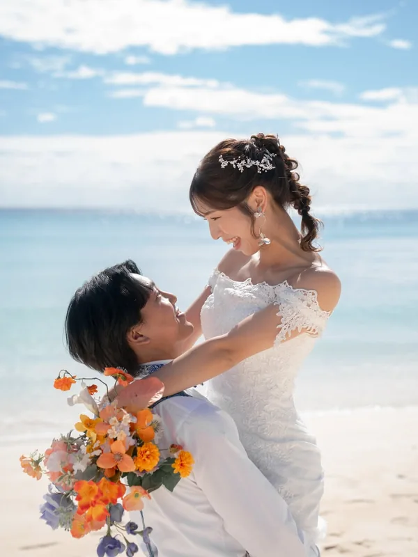 青い海を背に花嫁を抱き上げる新郎