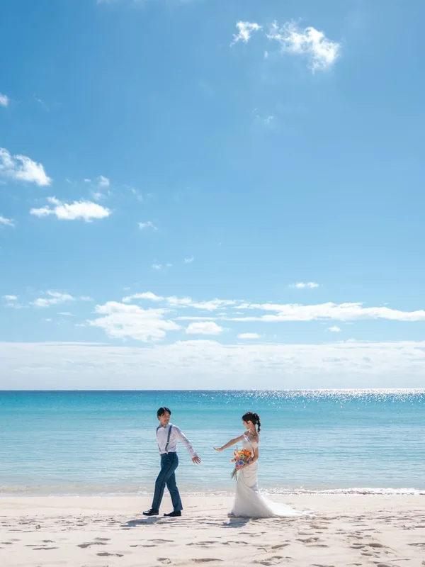 青空の下、白い砂浜を歩くふたり