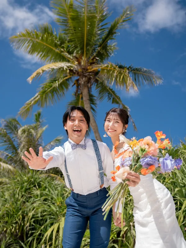 ヤシの木の下で、ブーケを手に笑うふたり
